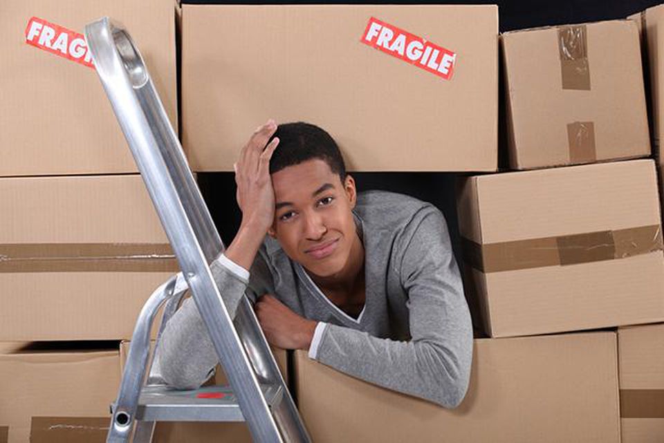 Mark Roemer image of a young man looking frustrated surrounded by boxes.
