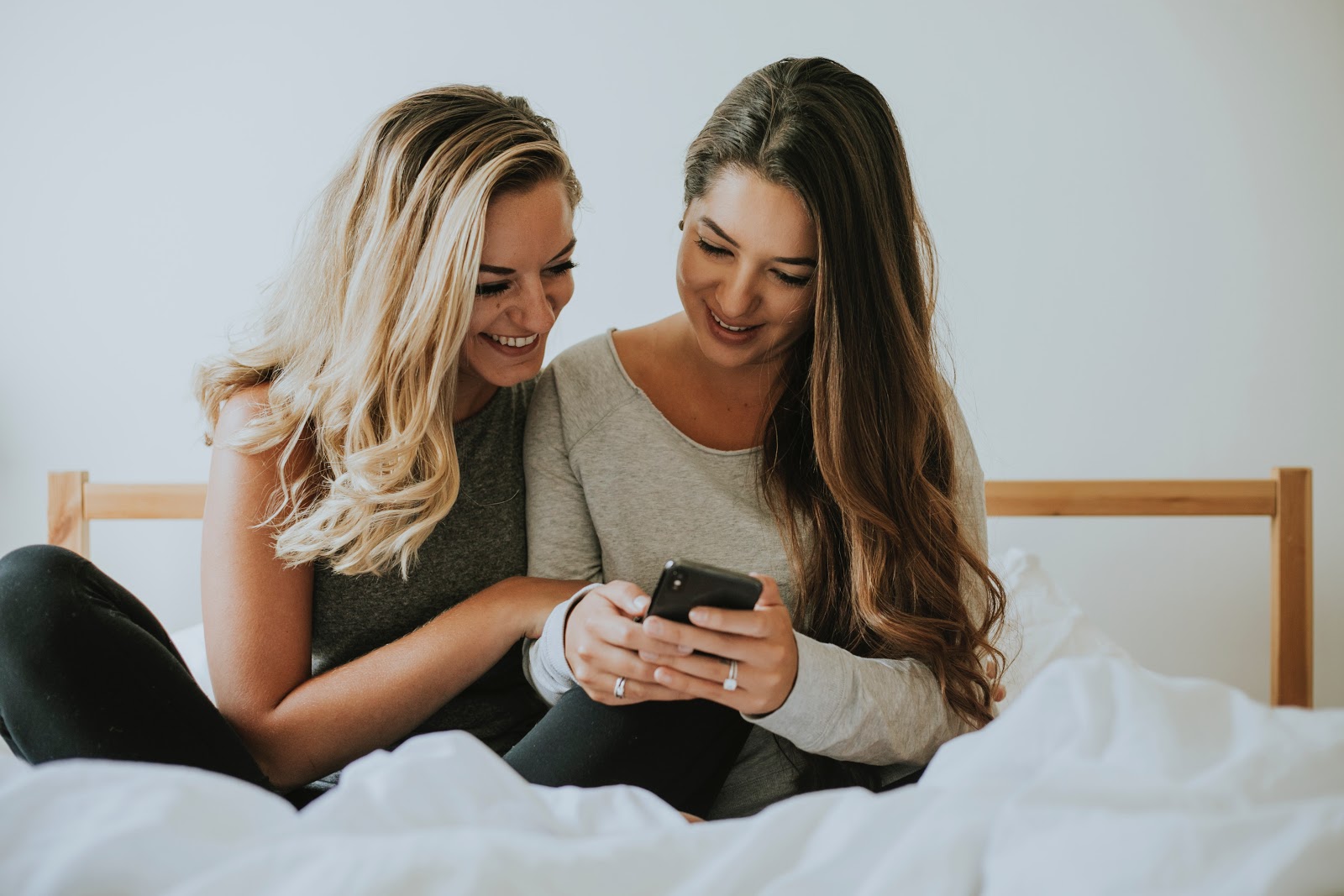 Mark Roemer image of two people sitting on a bed that appear to be roommates looking at a phone