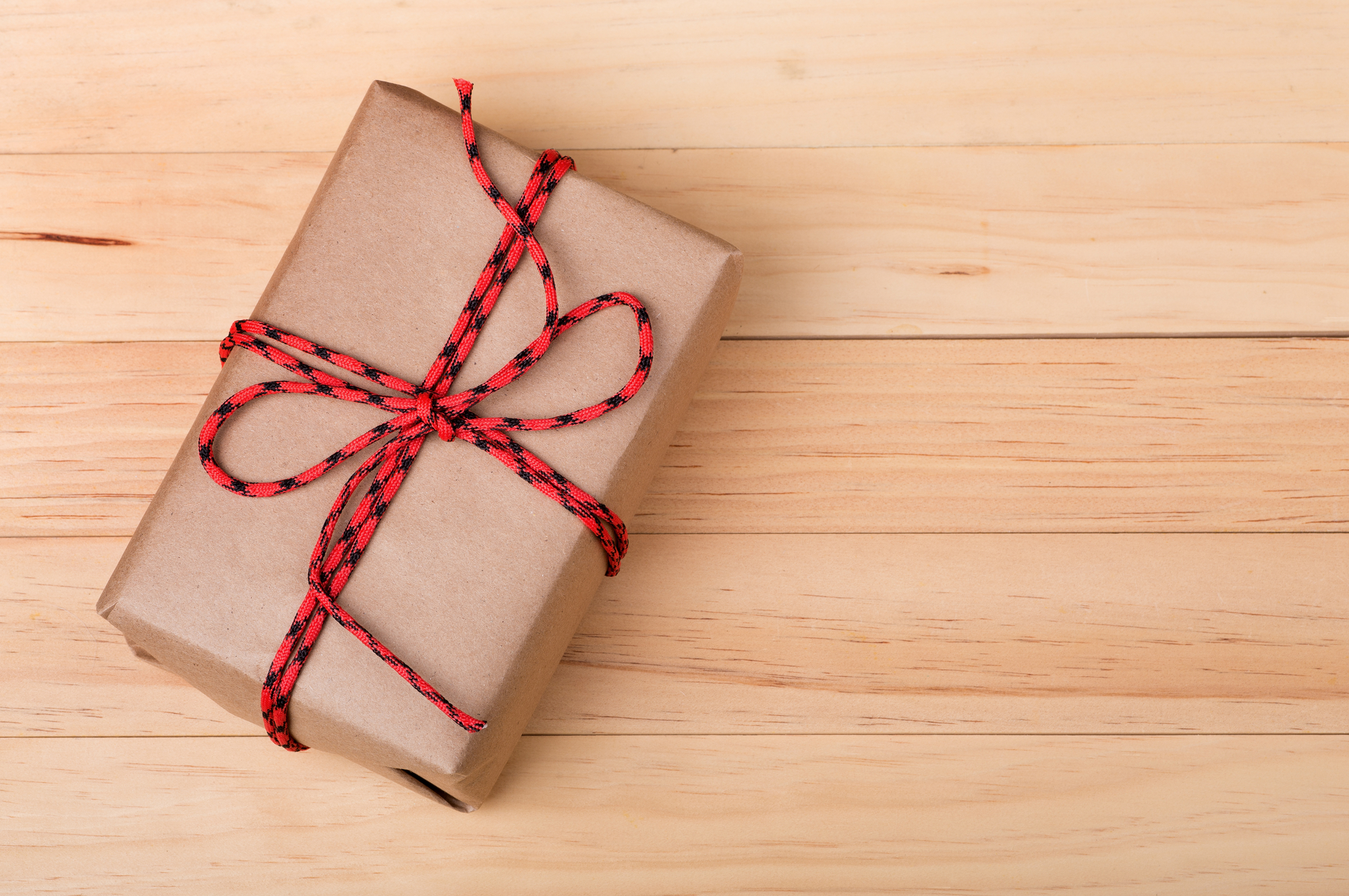 Mark Roemer image of a brown package with red ribbon sitting on a wooden desk