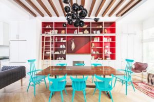Mark Roemer image of a home with bold colors such as bright blue chairs and bright read accent for dishes.